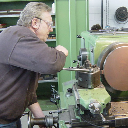 Mann arbeitet an einer Drehbank.
