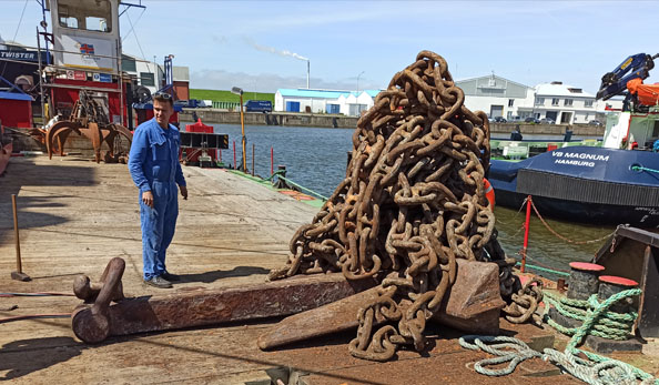 Ein Arbeiter steht neben einem Haufen Ankerkette.